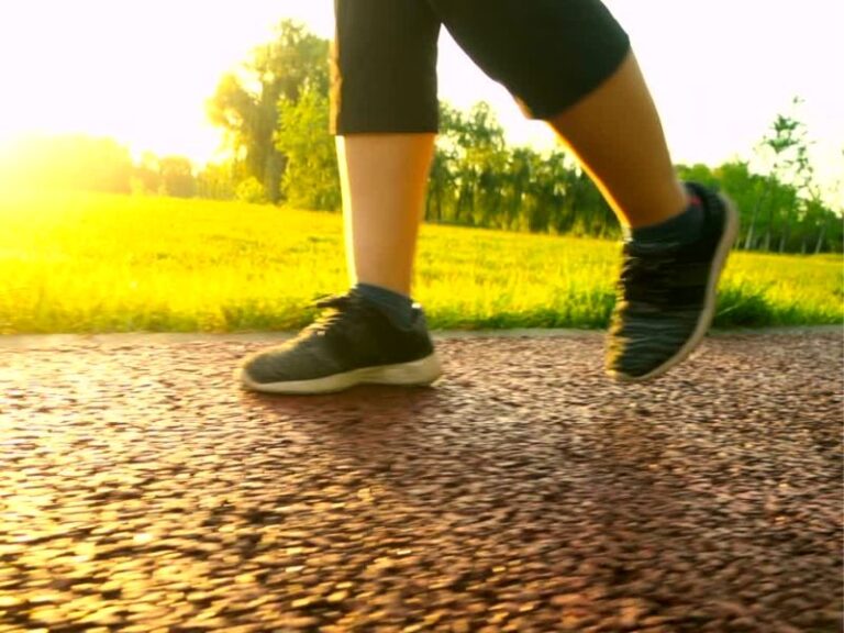 Devojka sa crnim helankama i patikama šeta stazom u prirodi