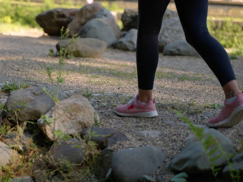 Devojka u roze patikama i crnim helankama šeta u prirodi